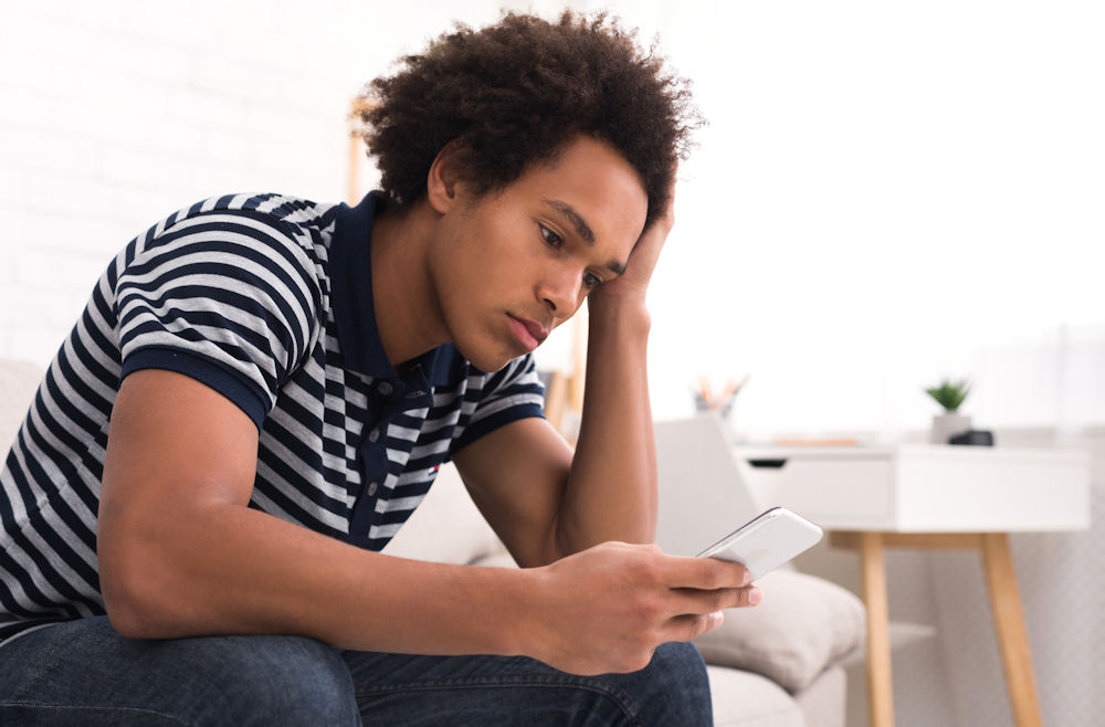 A man scrolling through his phone reading about addiction prevention