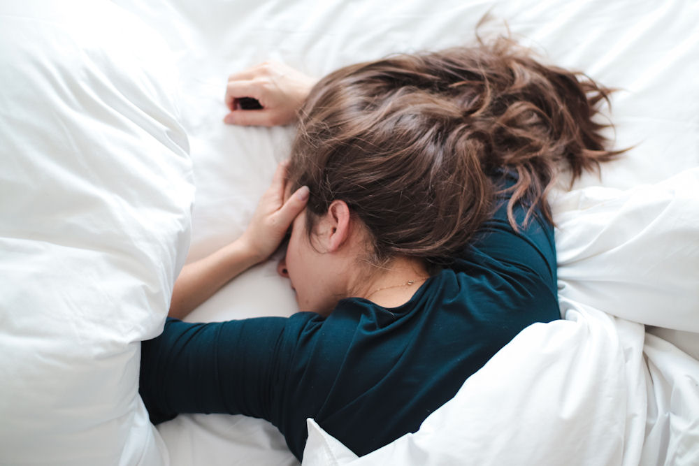Woman lying in bed coping with hangover anxiety